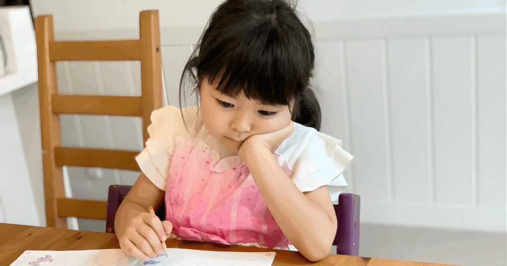 机に向かって座る子どもの写真。日常の姿勢や習慣が歯並びに影響する背景を説明する記事内画像。